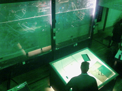 IMAGE: Looking down into a control room within the bunker, lit with green lights.