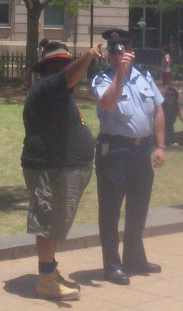 Sam Watson, rally organiser, discusses details with a police senior-sergeant 2 - Justice for Mulrunji Rally at Queens Park and March through Brisbane City, Australia, November 18 2006