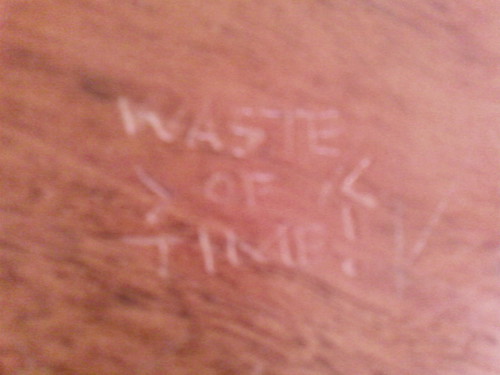 IMAGE: WASTE OF TIME etched into a council office desk.