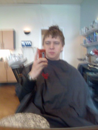 David i frisörstolen före ingreppet med en mobiltelefon i handen