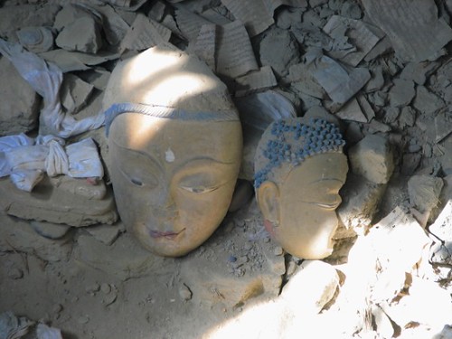 Broken Buddha faces and piles of pecha