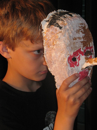A child holding a mask in front of his face.