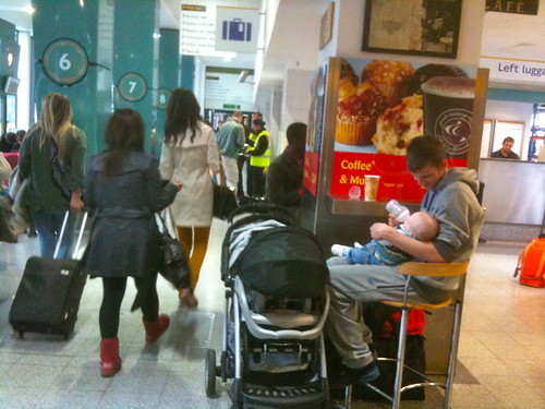Father feeding baby at train station in London