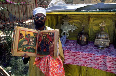An Ethiopian Orthodox priest displaying an antique bible with a depiction of St. George on horseback slaying a dragon (sacredsites.com)