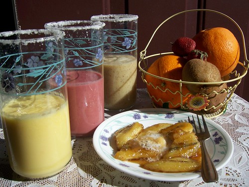 Chilled glasses with Sugar around the rim with Orange,Strawberry,Kiwi Milkshakes  with Plateful of Whipped Creamy Caramalized Banana 