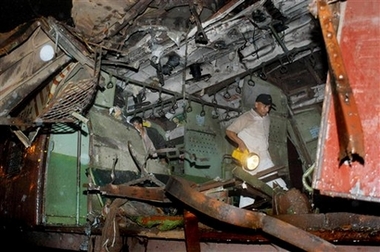 A rescue worker surveys the interior of a destroyed train, Bombay