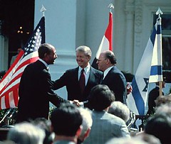 Egyptian President Anwar al-Sadat, left, shakes hands with Israeli Prime Minister Menachem Begin at the signing of a peace treaty in Washington, D.C., in 1979. United States President Jimmy Carter, center, helped negotiate the treaty between Egypt and Israel by bringing the two leaders together at Camp David, Maryland, in 1978.